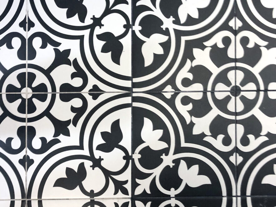 Les carreaux de sol noirs et blancs aux motifs floraux et géométriques répétitifs évoquent l'élégance intemporelle de l'architecture haussmannienne.