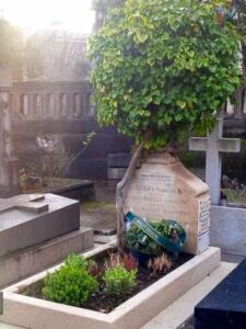Une pierre tombale à Paris, capturée sur une photo ancienne, est poussée de côté par les racines d'un arbre qui pousse depuis la tombe, avec une couronne commémorative verte à la base - un témoignage silencieux de l'histoire et de la nature qui s'entremêlent.
