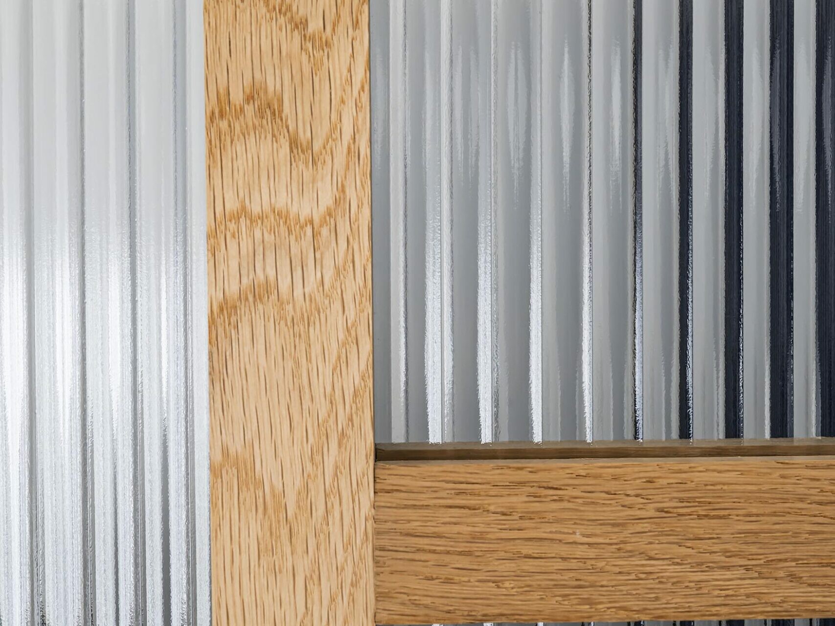 Des poutres en bois verticales et horizontales se croisent devant des panneaux de verre nervurés et translucides, évoquant l'élégante structure que l'on retrouve souvent dans un appartement haussmannien.