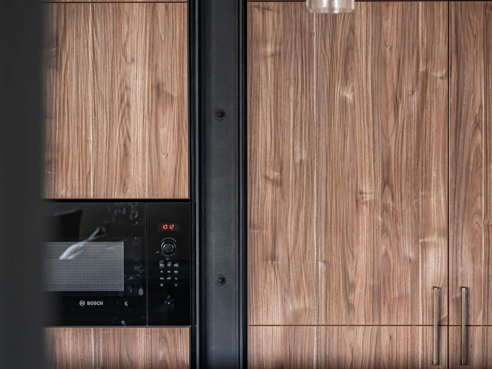 Cuisine moderne de style scandinave avec des placards lambrissés, un micro-ondes Bosch encastré, une poutre métallique noire, un plan de travail en marbre et une suspension en verre : idéale pour la rénovation de n'importe quel appartement.